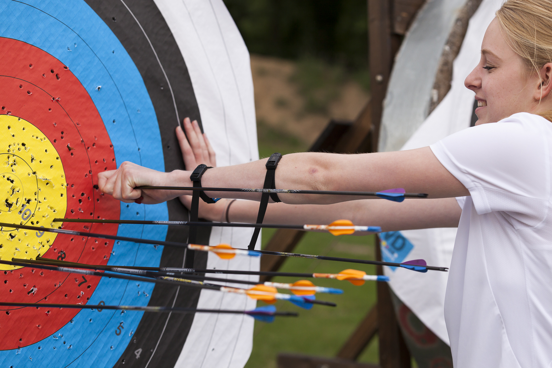 Junge Frau zieht Pfeile aus einer Zielscheibe.